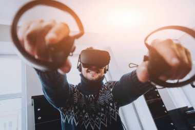 Mutlu genç adam ofiste bir oyun oynuyor. Sanal gerçeklik kulaklık.