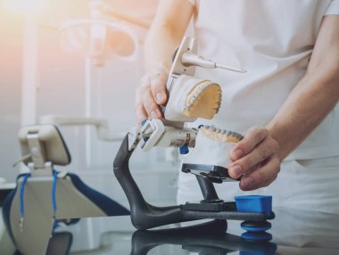 Diş teknisyeni, diş laboratuarında eklem makinesi ile çalışıyor.