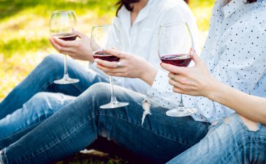 Üç kız parkta kırmızı şarap gözlüklü. Kırpılmış.