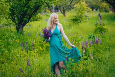 Çiçeklerle parkta güzel bir hamile kadın