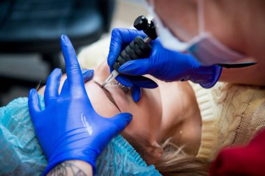 Profesyonel dövmeci kaş dövme bir kız yapar. Estetik tıp