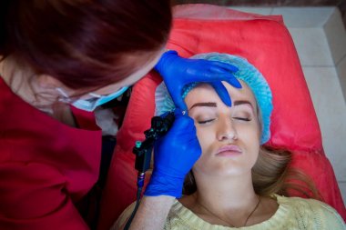 Profesyonel dövmeci kaş dövme bir kız yapar. Estetik tıp