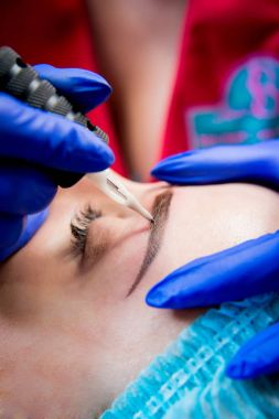 Profesyonel dövmeci kaş dövme bir kız yapar. Estetik tıp