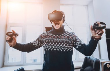 Mutlu genç adam ofiste bir oyun oynuyor. Sanal gerçeklik kulaklık.