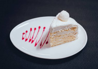 Siyah masa örtüsü üzerinde beyaz tabakta kremalı pasta