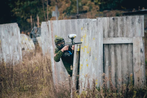 Man with gun playing at paintball. Outdoors.