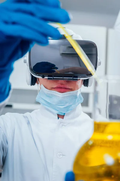 Laboratory assistant at work in virtual reality glasses examines the drug in laboratory.