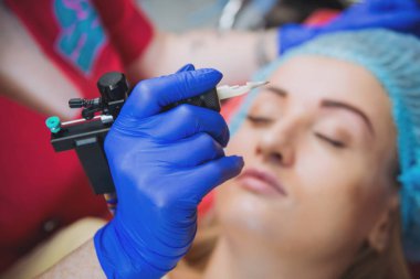 Profesyonel dövmeci kaş dövme bir kız yapar. Estetik tıp