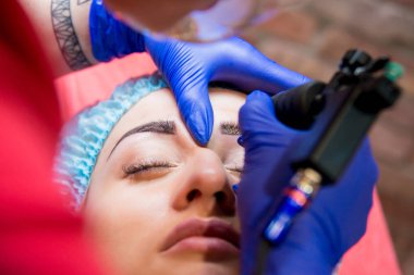 Profesyonel dövmeci kaş dövme bir kız yapar. Estetik tıp