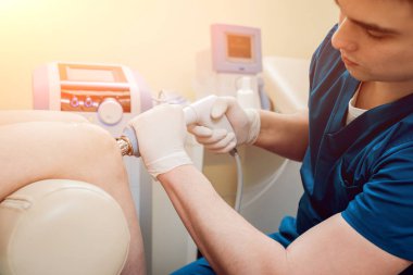 Şok dalga tedavisi. Manyetik alan, rehabilitasyon. Fizyoterapist doktor ameliyat bir hastanın diz üzerinde gerçekleştirir.