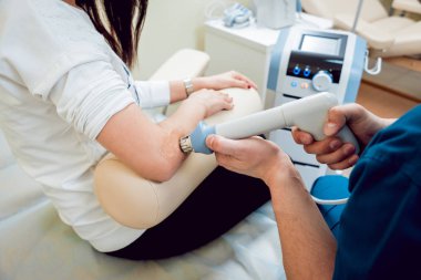 Şok dalga tedavisi. Manyetik alan, rehabilitasyon. Fizyoterapist doktor ameliyat bir hastanın dirsek üzerinde gerçekleştirir.