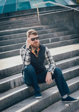 Yakışıklı adam açık havada kameraya poz rahat kıyafetler içinde sakallı