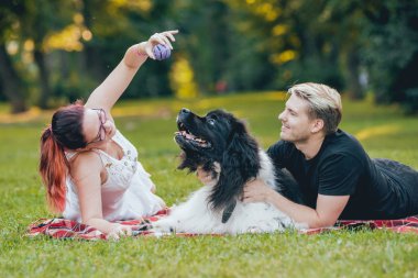 Genç çift yeşil park ile siyah ve beyaz Newfoundland köpek çalış