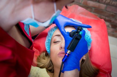 Profesyonel dövmeci kaş dövme bir kız yapar. Estetik tıp