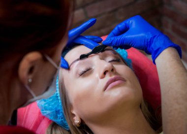 Profesyonel dövmeci kaş dövme bir kız yapar. Estetik tıp