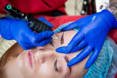 Profesyonel dövmeci kaş dövme bir kız yapar. Estetik tıp