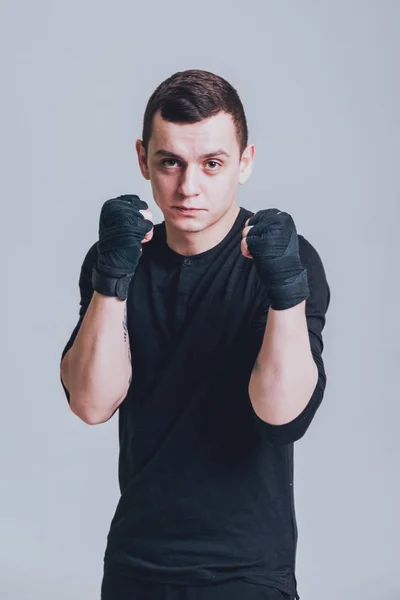 Young fighter posing in studio before grey wall