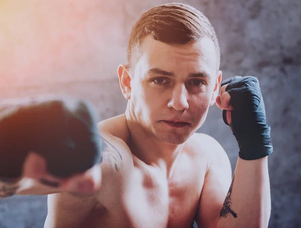 Young fighter posing in studio before grey wall