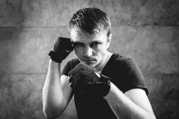 Young fighter posing in studio before grey wall