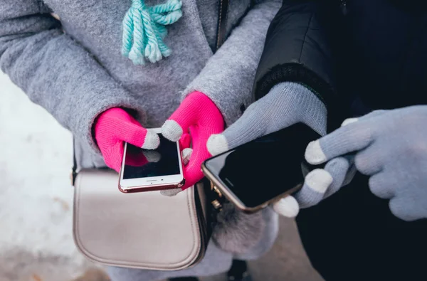Couple using smartphone with gloves for touch screens in winter