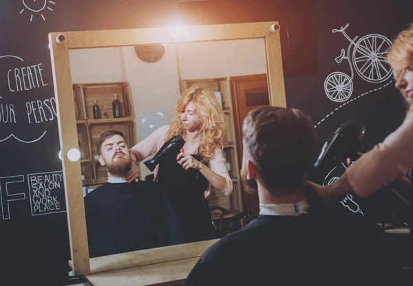 Hairdresser makes hairstyle for a young man.