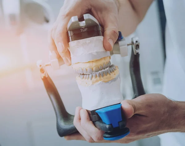 Dental technician working with articulator in dental lab