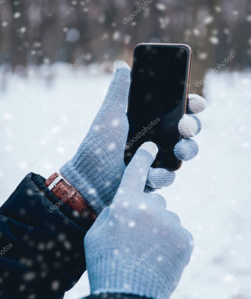 Man using smartphone with grey gloves for touch screens in winter