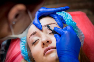 Profesyonel dövmeci kaş dövme bir kız yapar. Estetik tıp