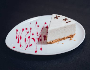 Siyah masa örtüsü üzerinde beyaz tabakta kremalı pasta