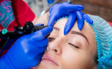 Profesyonel dövmeci kaş dövme bir kız yapar. Estetik tıp