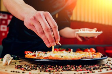 Aşçı pizza yapıyor. Malzemeler ekler. Bir restoran