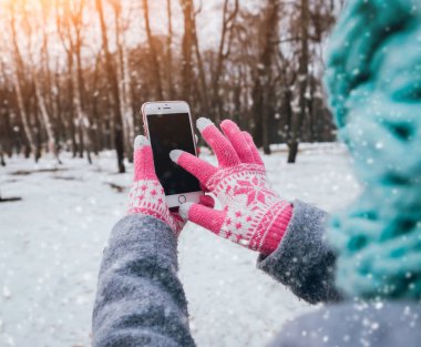 Smartphone ile pembe eldiven dokunmatik ekranlar için kışın kullanan kadın.