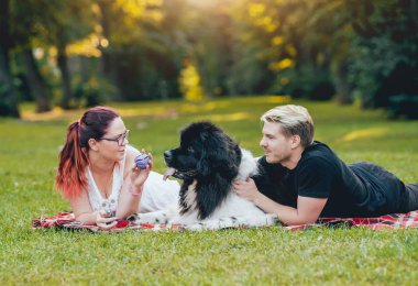 Genç çift yeşil park ile siyah ve beyaz Newfoundland köpek çalış