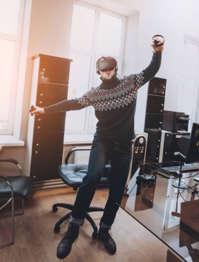 Mutlu genç adam ofiste bir oyun oynuyor. Sanal gerçeklik kulaklık.