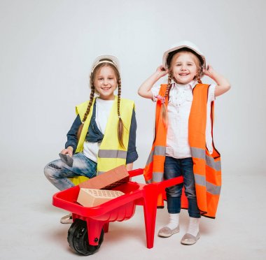 Onarım veya inşaat beyaz üzerinde oynarken örgüler ile iki küçük neşeli kız