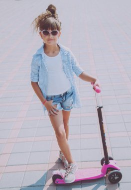 Güneşli bir gün, sokakta küçük kız sürme scooter