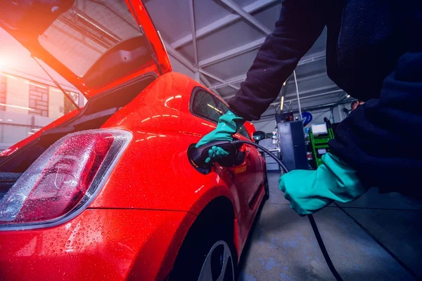 Charging an electric vehicle in the car service. Future of the automobile. Red colors