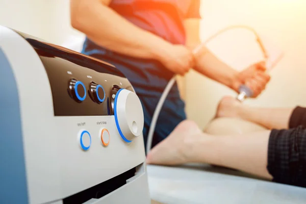 Shock wave therapy. The magnetic field, rehabilitation. Physiotherapist doctor performs surgery on a patients heel