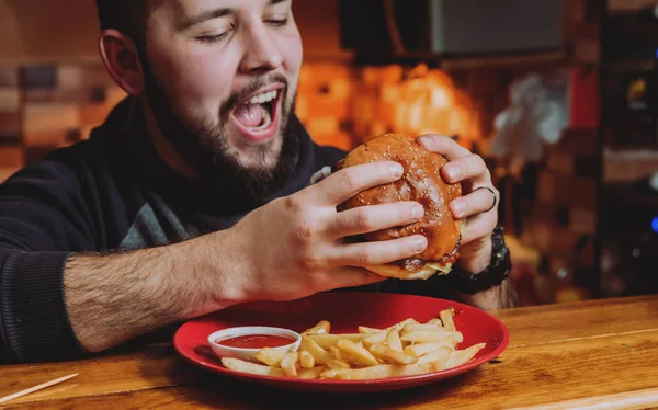 Young man eating cheeseburger in restaurant