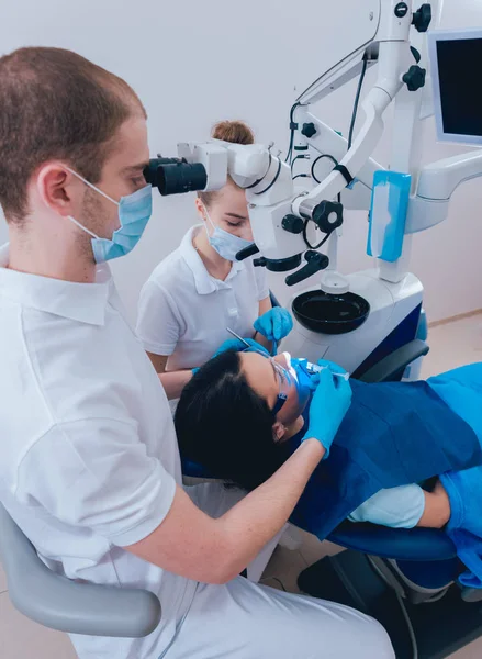 Treatment of root canals under a microscope, work with an assistant. Modern technology