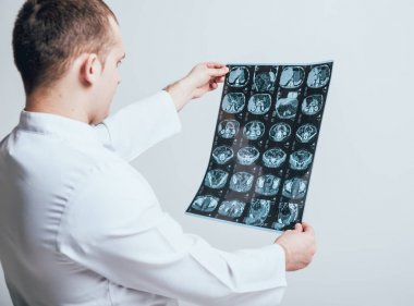 Erkek octor dikkatle MRI tarama beyaz duvar önce inceler