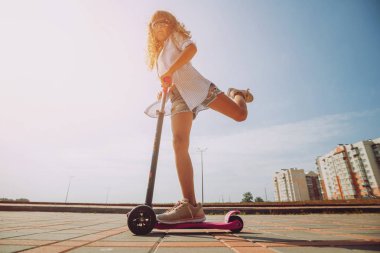 Güneşli bir gün, sokakta küçük kız sürme scooter