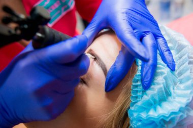 Profesyonel dövmeci kaş dövme bir kız yapar. Estetik tıp