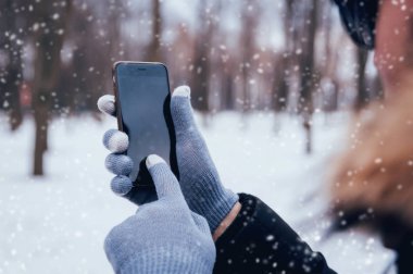 Smartphone ile gri eldiven dokunmatik ekranlar için kışın kullanan adam