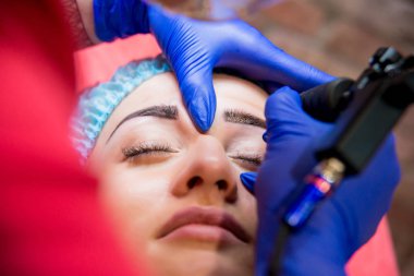 Profesyonel dövmeci kaş dövme bir kız yapar. Estetik tıp