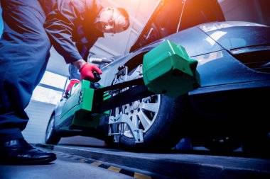 Araba tamircisi sensör süspansiyon ayarı sırasında yükleme. Tekerlek hizalama iş yerinde onarım servis istasyonu