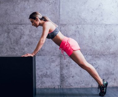 Studio poz ve farklı egzersizleri yapıyor genç atletik beyaz kadın.