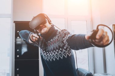 Mutlu genç adam ofiste bir oyun oynuyor. Sanal gerçeklik kulaklık.