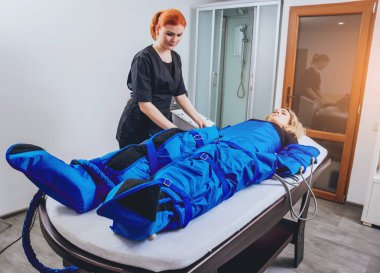 Genç kadın spa salonda. Pressotherapy Güzellik Merkezi kadında makinede. Kozmetik tıp cihazları