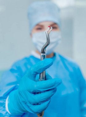 Çürüyen bir diş kaldırmak için cerrahi pense kullanarak dişçi. Modern diş Kliniği